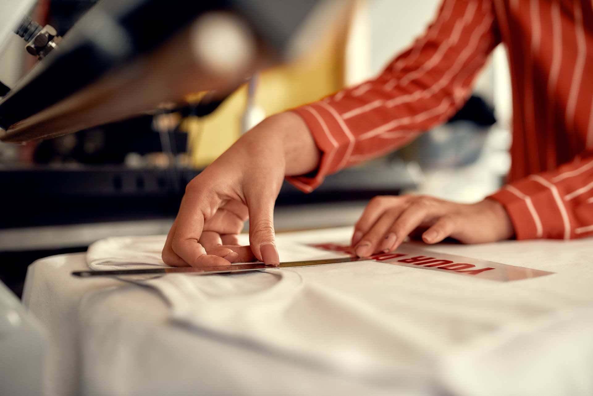 Devoted to brilliance. Cropped shot of woman hands trying on, moving advertisement sticker with text while preparing it to be printed on a T-Shirt